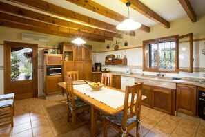 A kitchen with wooden cabinets, a dining table with chairs, and a window with decorative iron bars.