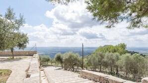 Eine steinerne Treppe führt zu einer Aussichtsplattform mit Blick auf sanfte Hügel und einen klaren Himmel.