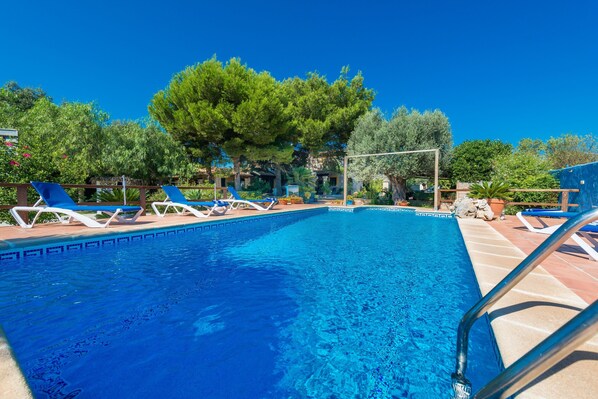 A swimming pool with lounge chairs and a pergola.