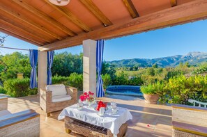 An outdoor patio with a table set for tea, surrounded by wicker furniture and blue-striped curtains, overlooking a mountainous landscape and a swimming pool. - CAN REURE (CAN PARIS) - Villa with private pool in Inca. Free WiFi (Inca)
