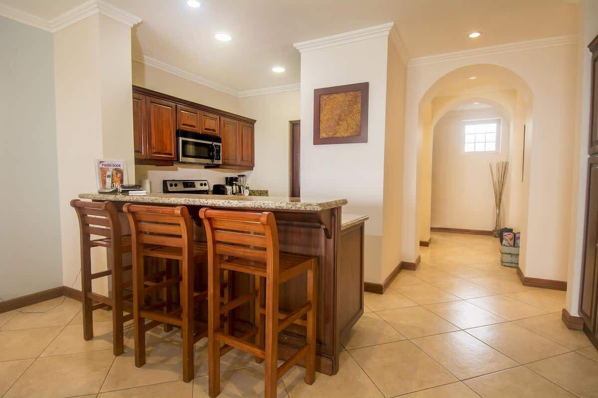 Una cocina con taburetes de madera, microondas y cafetera.