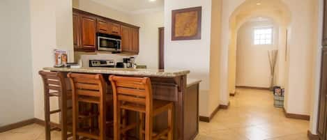 Una cocina con taburetes de madera, microondas y cafetera.
