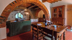 A rustic dining area with a wooden table, chairs, and a green plaid sofa. - Stunning private villa for 17 people with private pool, WIFI, TV, veranda and panoramic view (San Pancrazio)