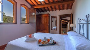 A bedroom with a bed, a tray of breakfast, a window with a view, and wooden beams on the ceiling. - Stunning private villa for 17 people with private pool, WIFI, TV, veranda and panoramic view (San Pancrazio)
