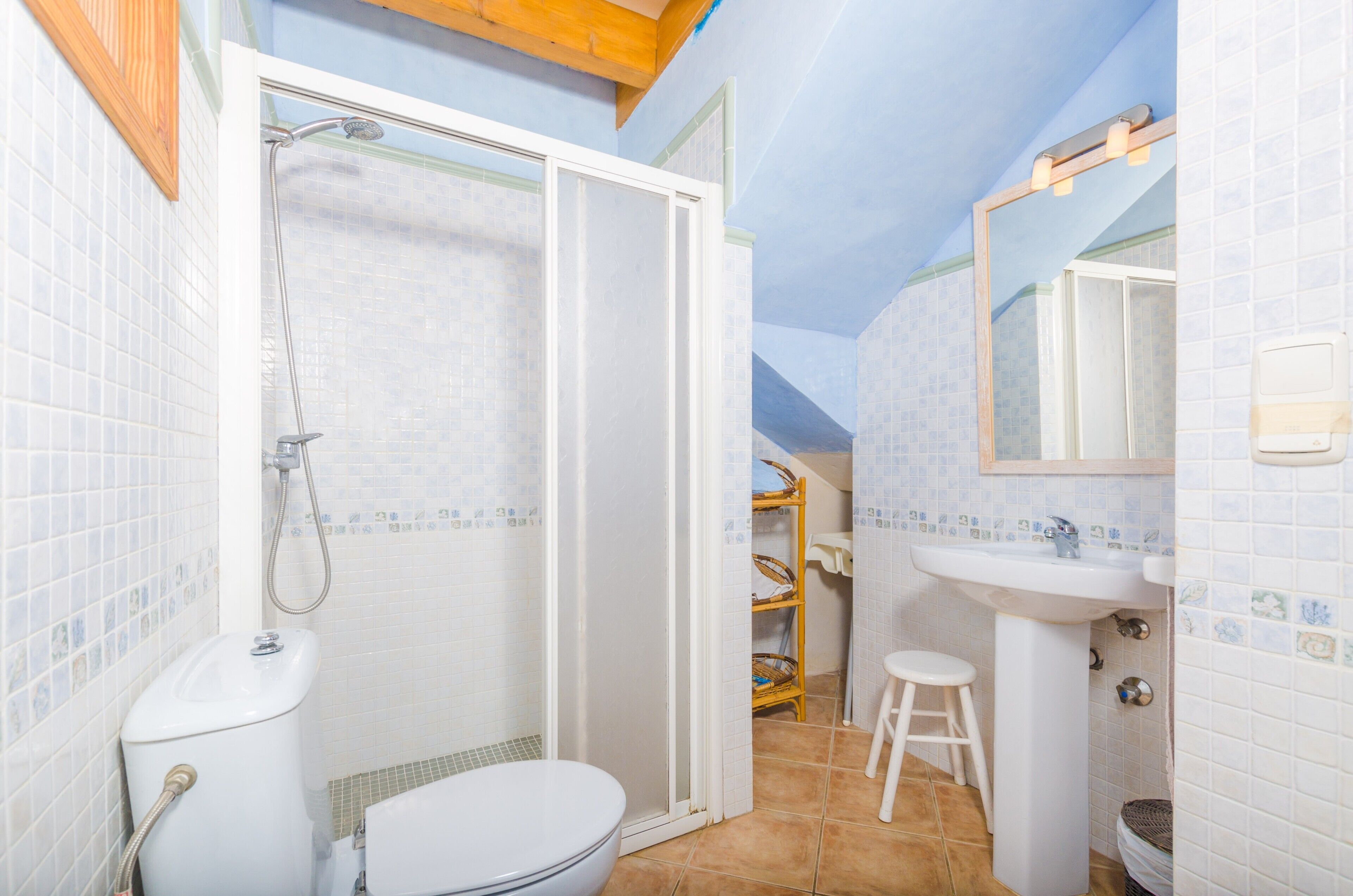 A bathroom with a shower, toilet, sink, and a mirror.