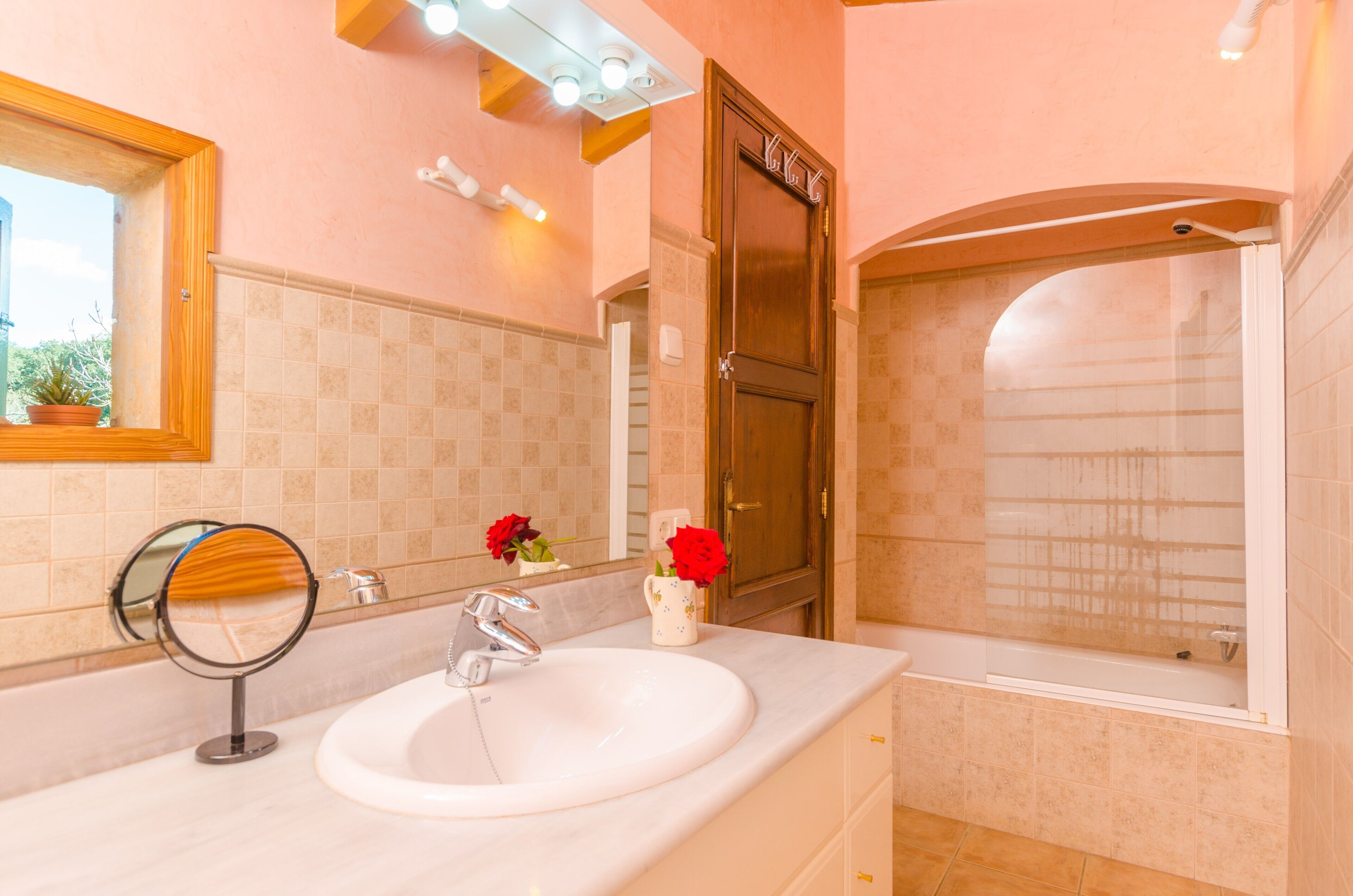 A bathroom with a sink, mirror, and shower.