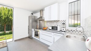 Une cuisine moderne avec des armoires blanches, une hotte de cuisinière en acier inoxydable, un four à micro-ondes et un four encastré.