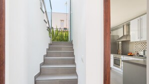 Un escalier menant à une cuisine moderne avec vue sur un balcon.