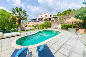 A swimming pool with lounge chairs and a stone staircase leading to a house.