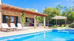 A swimming pool with lounge chairs, a pergola, and a stone building with shutters. - CORREFOC - Beautiful villa with private pool in quiet residential area. Free WiFi (Sa Pobla)