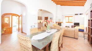 A spacious living area with a dining table, wicker furniture, and a fireplace. - CORREFOC - Beautiful villa with private pool in quiet residential area. Free WiFi (Sa Pobla)