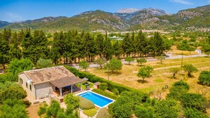 Une villa avec piscine, entourée d’arbres et de montagnes.