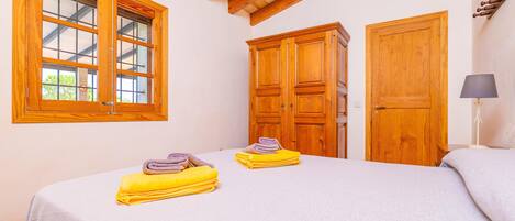 A bedroom with a bed, wooden wardrobe, and a window.