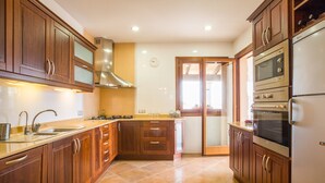 Uma cozinha com armários de madeira, coifa de aço inoxidável, forno duplo e geladeira.