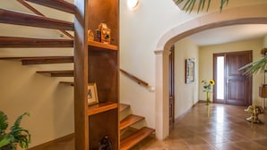 Uma escadaria com corrimãos de madeira e um prateleira com objetos decorativos.