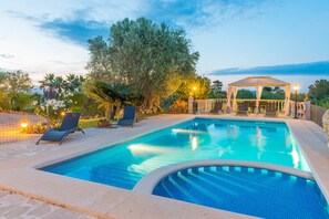 A swimming pool with lounge chairs, a gazebo, and a view of the sea.