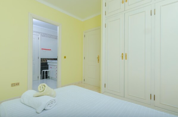 Habitación de hotel con una cama, un armario y un baño visible a través de una puerta abierta.