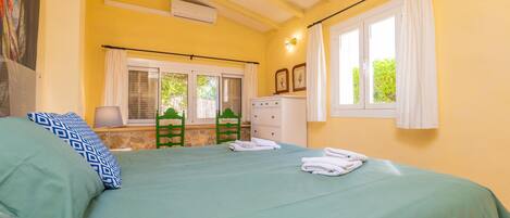 A room with a bed, a window with curtains, a dresser, and a chair.