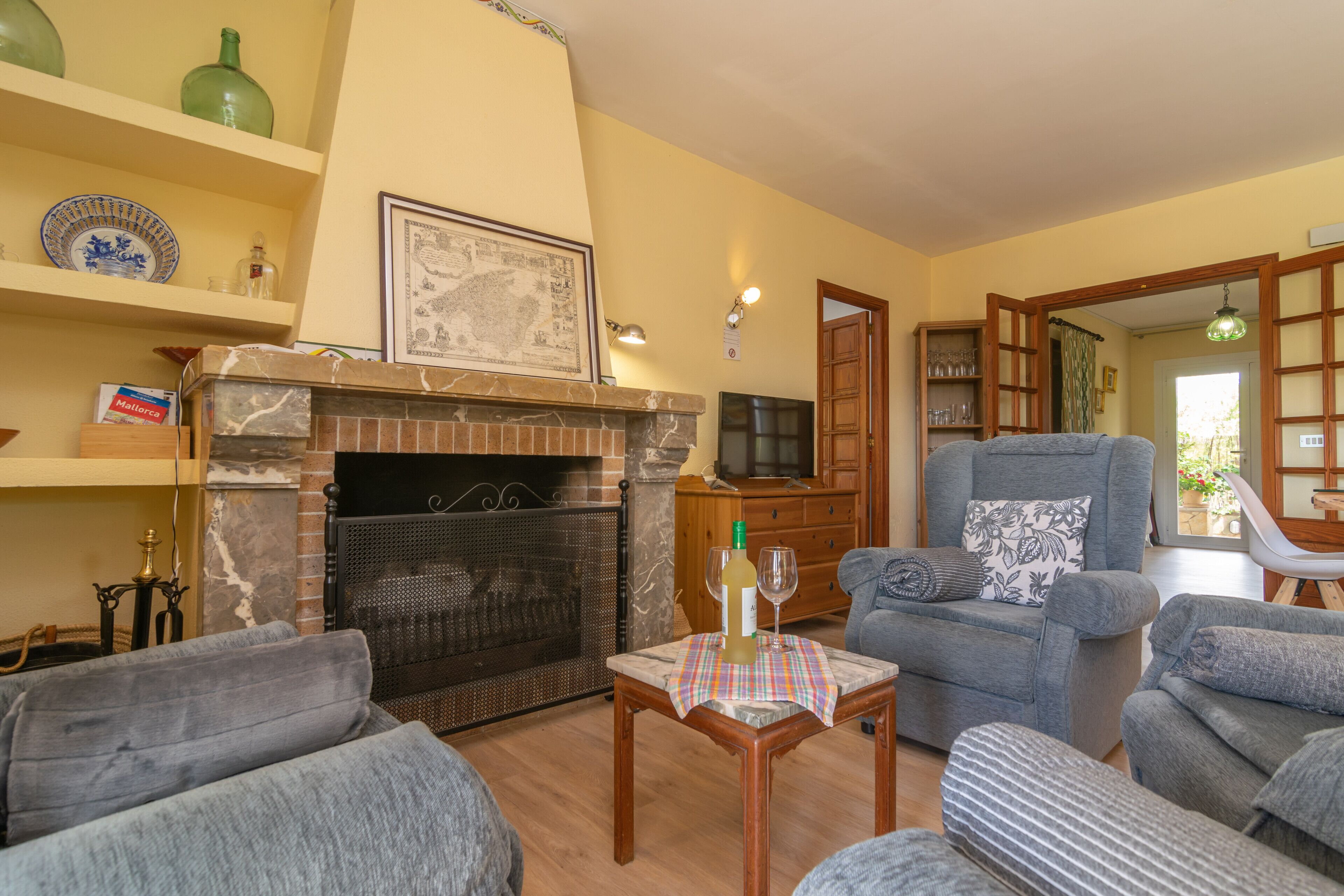 Ein Wohnzimmer mit Kamin, Sofas, einem Tisch mit Flasche und Glas sowie einem Fernseher.
