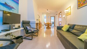 A living room with a flat-screen TV, a sofa, a dining table, and a chair. - CAN MIQUEL (CAN PICAFORT) - Chalet with terrace in Ca'n Picafort. Free WiFi (Muro)