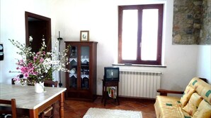 Un salon comprenant une table à manger, un canapé, un meuble, un téléviseur et une fenêtre.
