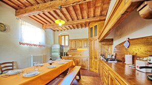 A rustic kitchen with wooden cabinets, a dining table set for four, and a bench. - Stunning private villa with private pool, hot tub, A/C, WIFI, TV, panoramic view, close to Florence (San Casciano In Val Di Pesa)