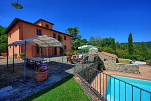 A villa with a swimming pool, outdoor seating, and a garden.