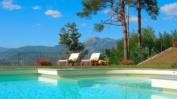 Une piscine avec deux chaises longues et une vue sur les montagnes en arrière-plan.