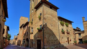 A narrow street in the town of Certaldo Alto with historic brick buildings, some with flower boxes on the windowsills. - Nice apartment for 3 guests with WIFI, A/C, TV and panoramic view, close to San Gimignano (Certaldo)