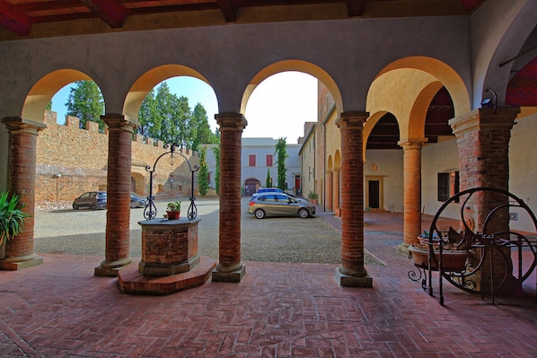 An indoor courtyard with brick flooring, arches, and columns.