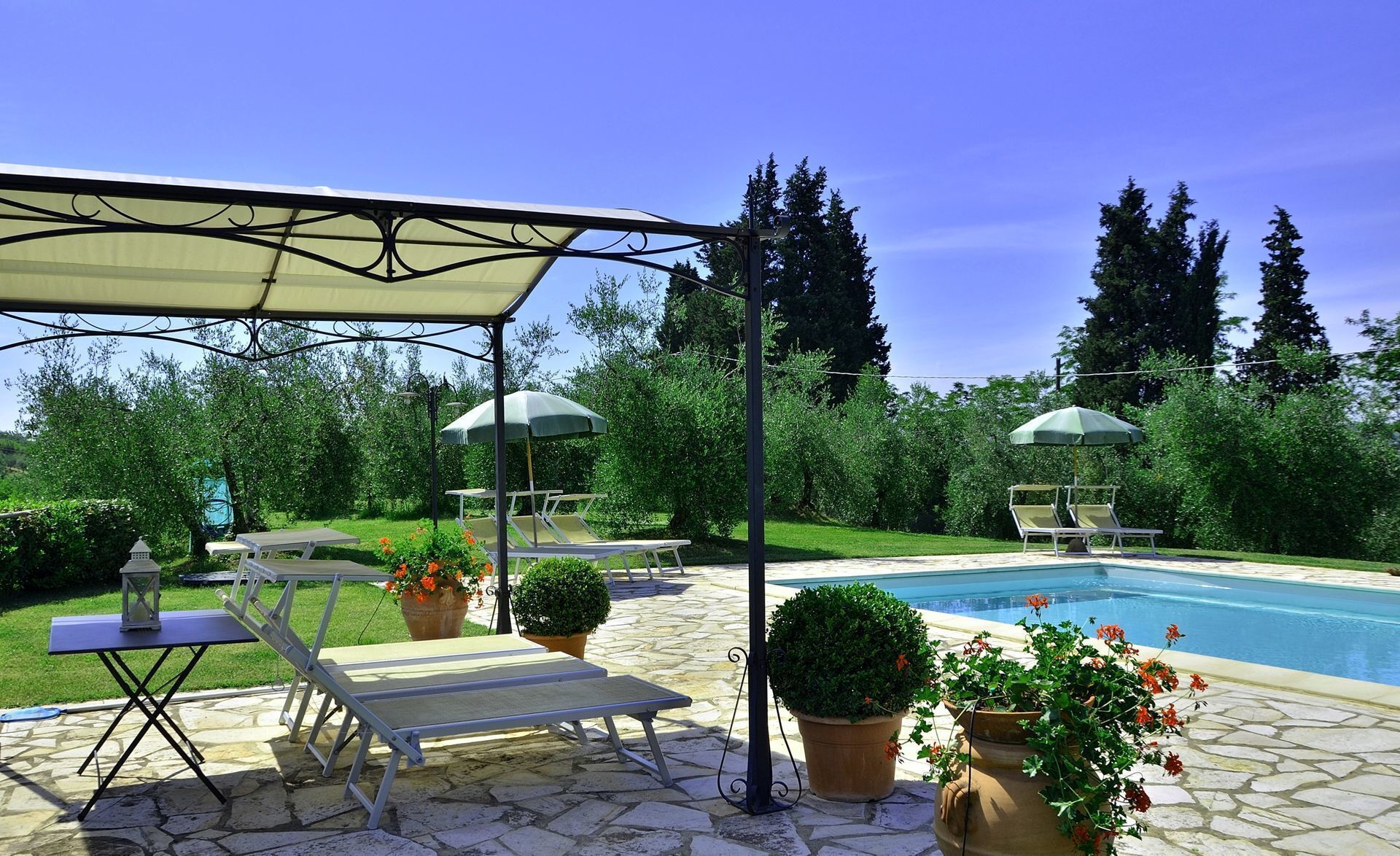 A poolside area with lounge chairs, a table, and umbrellas.