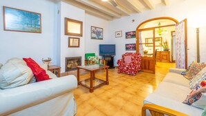 Una sala de estar con chimenea, televisor y comedor con mesa y sillas de madera.