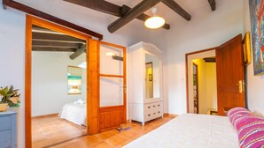 Un dormitorio con cama, cómoda, espejo y puerta que da a otra habitación.