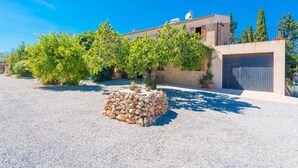 Un edificio con muro de piedra, garaje y camino de entrada de grava.