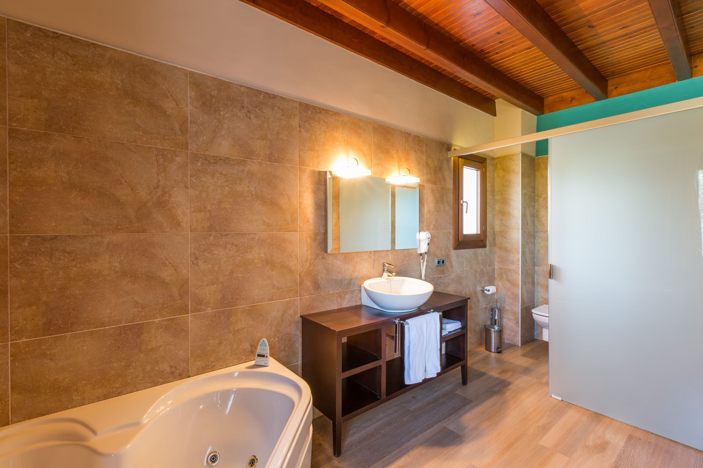 A modern bathroom with a large bathtub, a vanity with a sink, and a mirror.