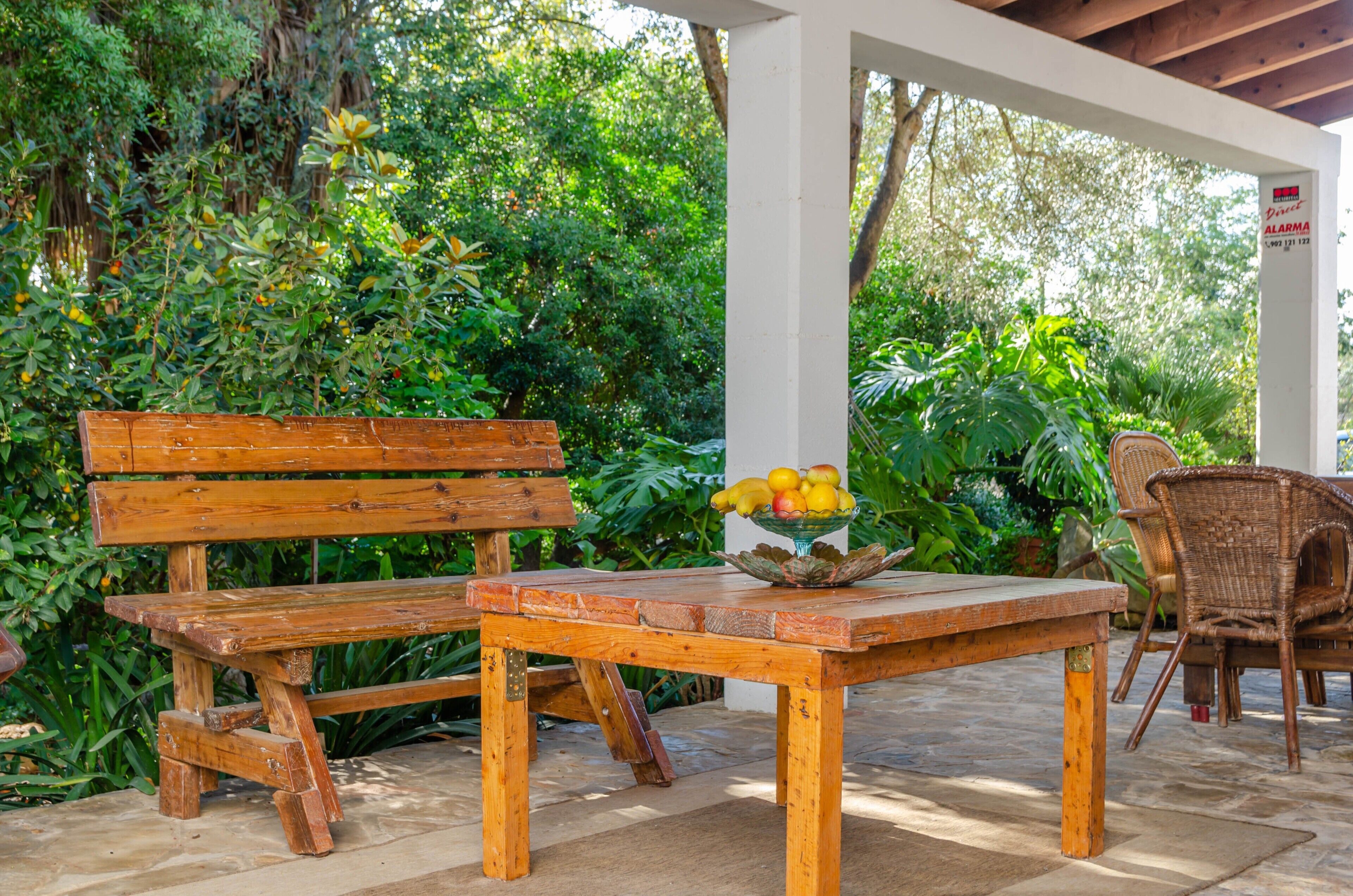 Ein Holzbänkschrank und Tisch auf einer Terrasse, auf dem Tisch steht eine Obstschale.