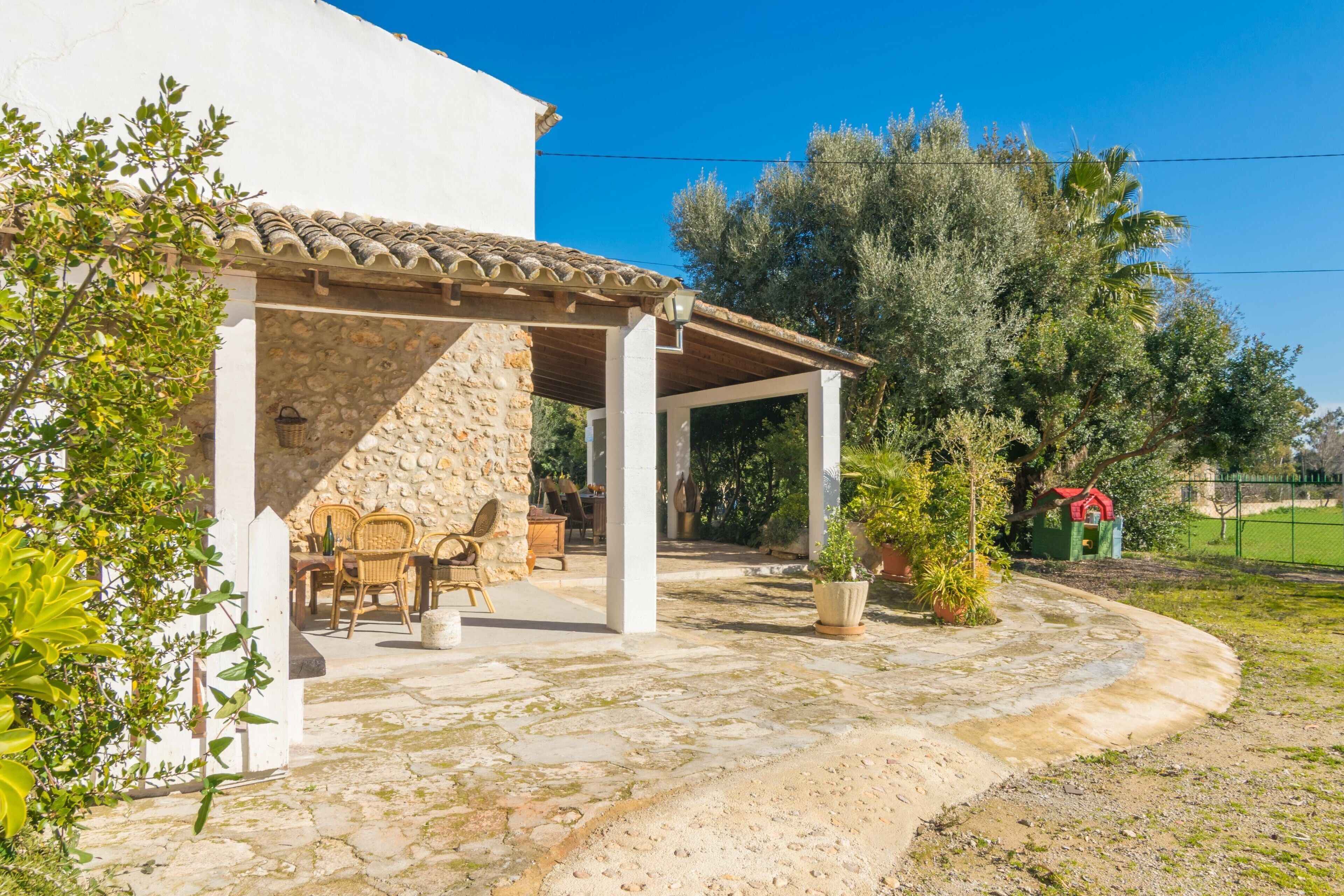 Un espacio de estar al aire libre cubierto, con pilares de piedra, una pared de piedra y un techo de baldosas.