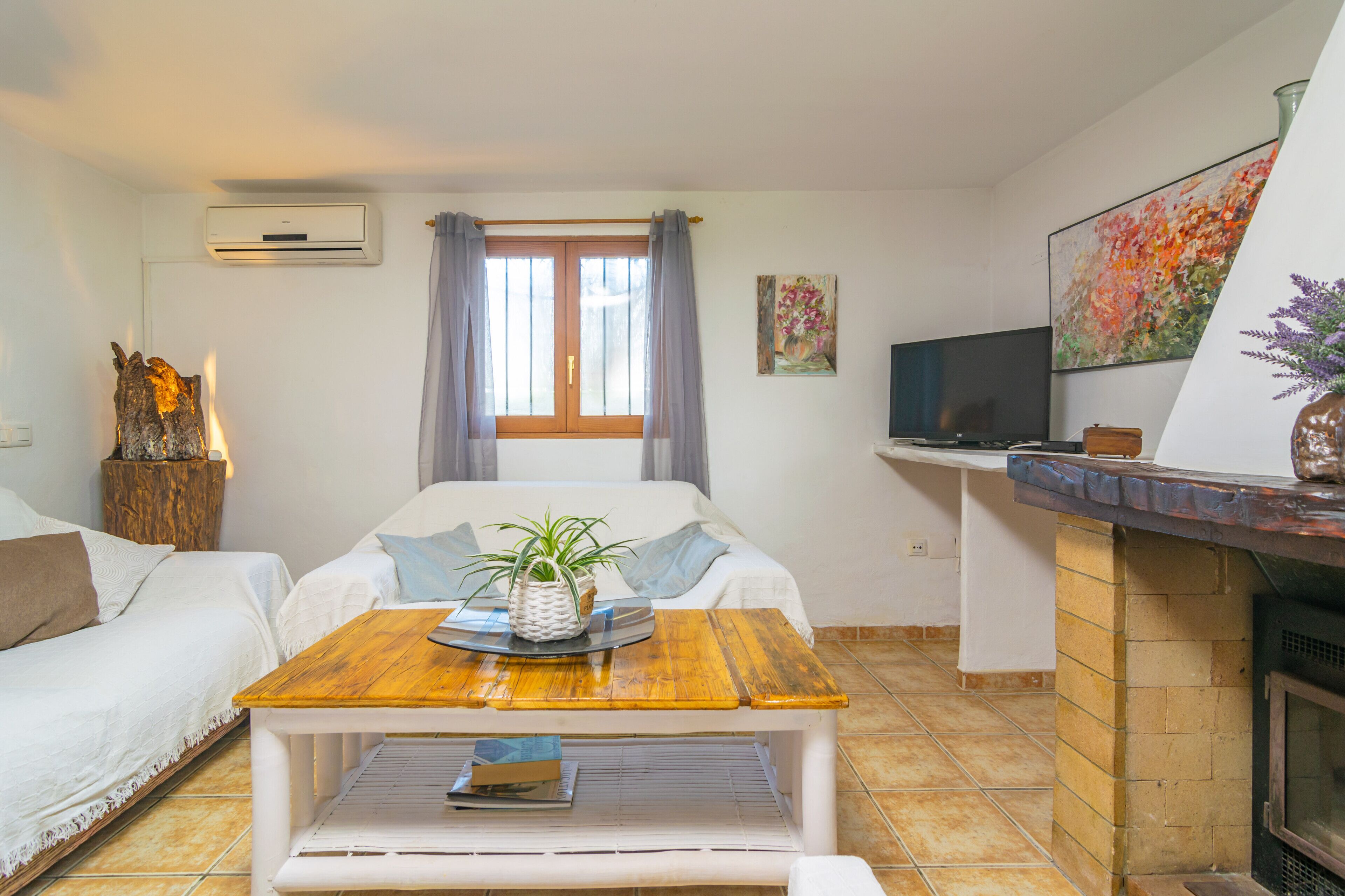 A cozy living room with a wooden coffee table, two white sofas, a television, and a fireplace.