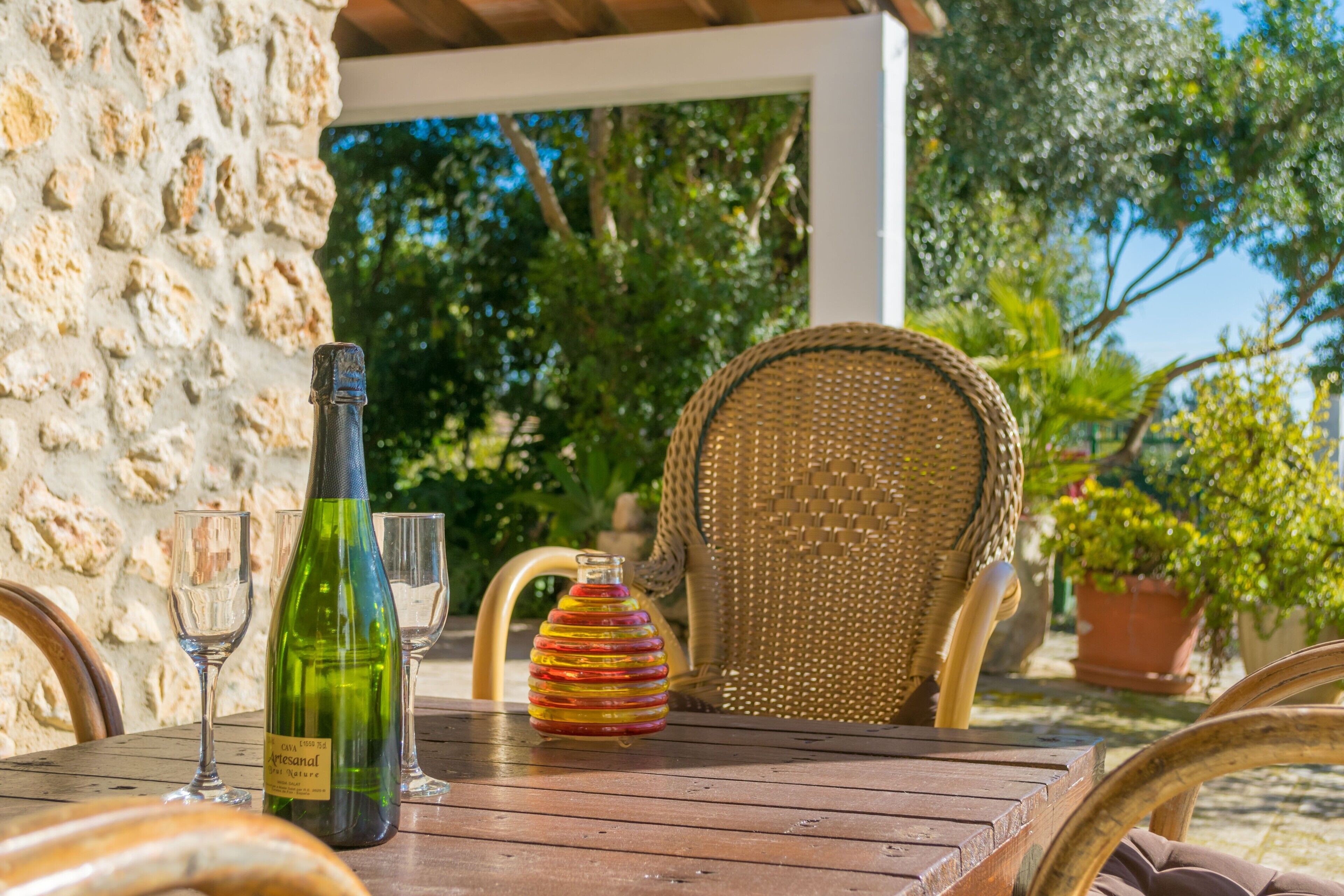 A wooden table with a wine bottle, two glasses, and a decorative vase.