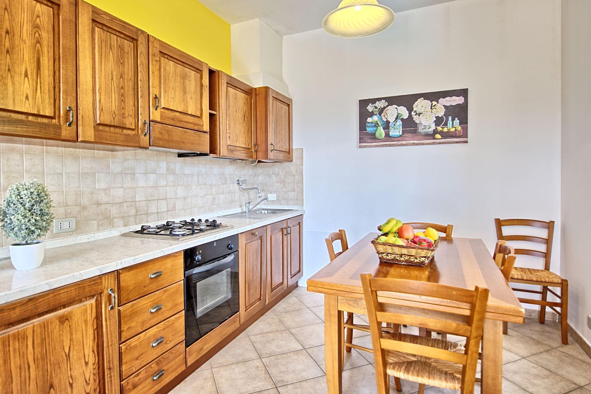 A kitchen with wooden cabinets, a gas stove, an oven, and a dining table with chairs.