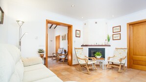 A living room with a sofa, wooden rocking chairs, a fireplace, and a dining area with a table and chairs. - WOODHOUSE - Beautiful townhouse with private pool, porch with BBQ and wonderful terrace. F (Ariany)