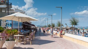 A beachfront promenade with outdoor seating, umbrellas, and beachside cafes. - CAN PONS - Chalet with terrace in Ca'n Picafort. Free WiFi (Can Picafort)