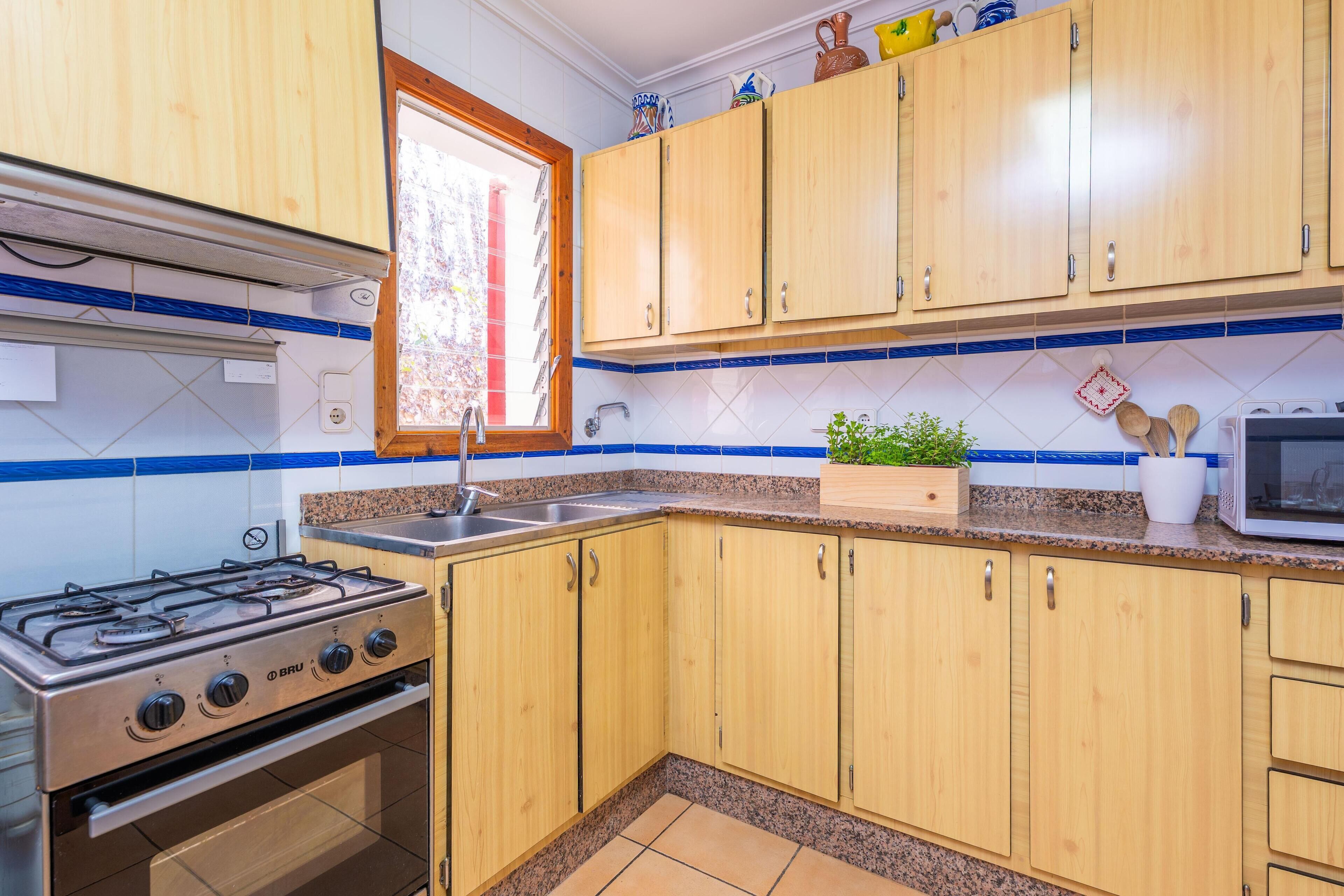 A kitchen with wooden cabinets, a gas stove, a microwave, and a window with a view.