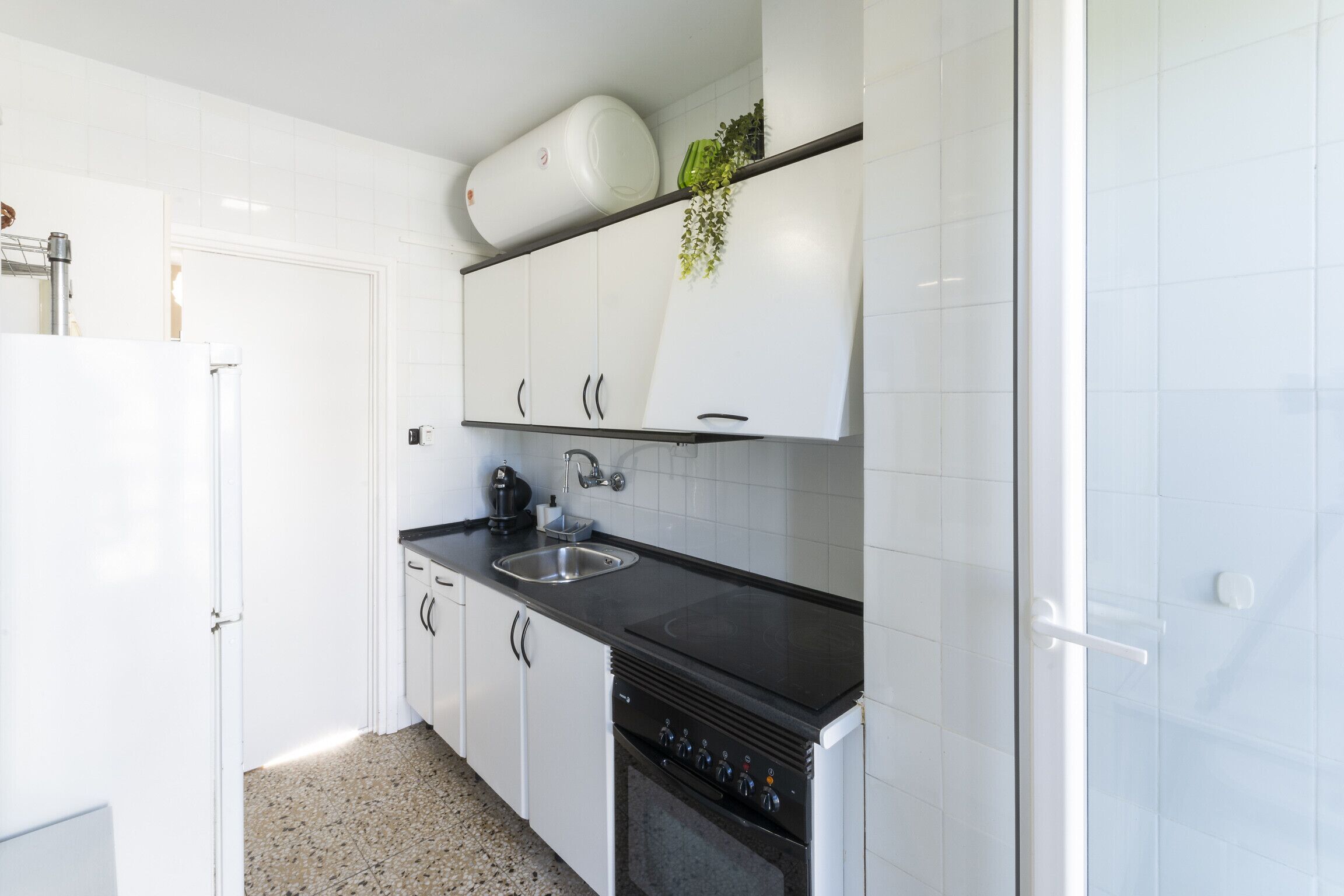 A modern kitchen with white cabinets, a black countertop, and a built-in oven.