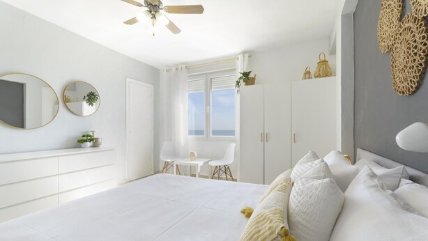 Une chambre à coucher avec un lit, un ventilateur de plafond, une fenêtre, un bureau et une chaise.