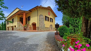 Una casa de dos pisos con fachada de piedra, exterior amarillo y tejado de tejas rojas.
