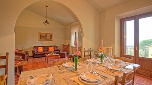 Un comedor con una mesa preparada para cuatro personas, un sofá y un cuadro en la pared.