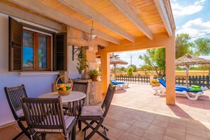 A covered patio with a table and chairs, a view of the garden, and outdoor seating. - VILLA CÉSAR - Villa with private pool and free Wifi in Campos (Campos)