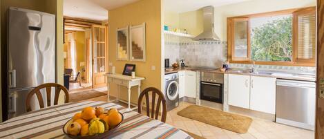 A kitchen with a dining area, a washing machine, and a refrigerator.