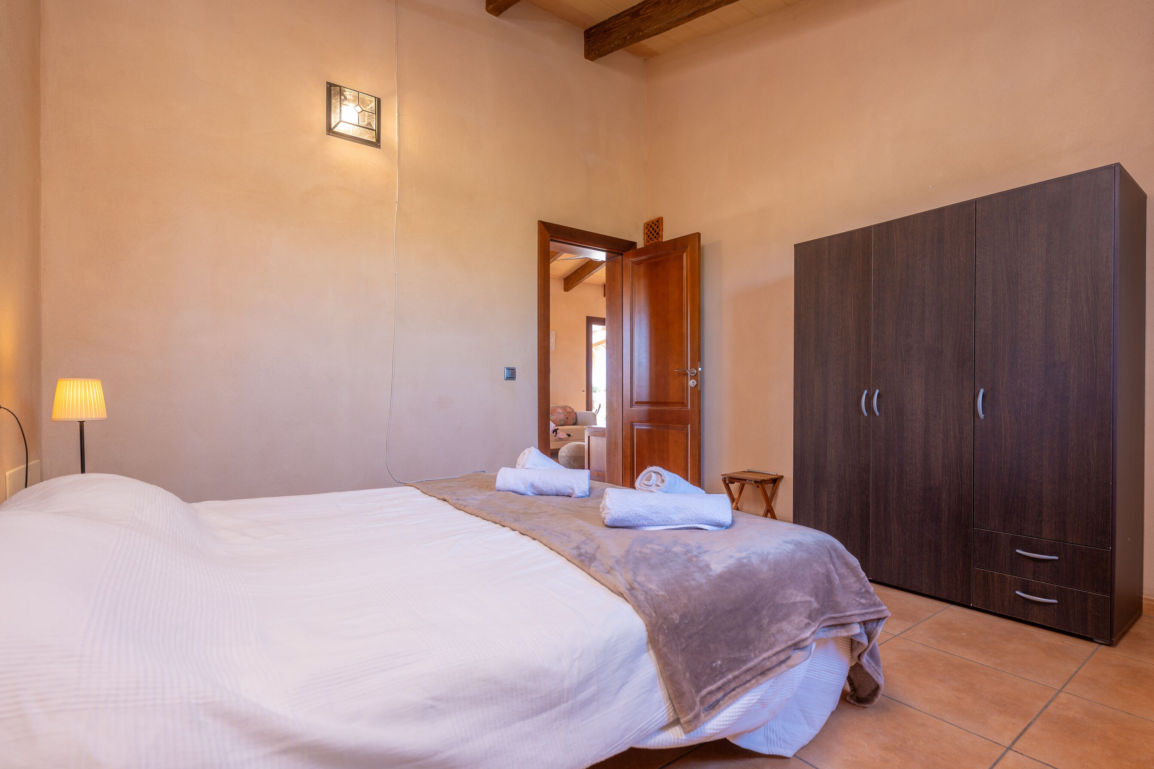 Un dormitorio con una cama grande, un armario y una lámpara.